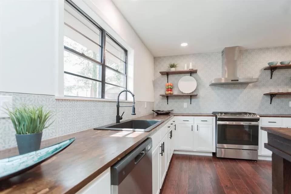 A kitchen with stainless steel appliances and wooden counter tops.