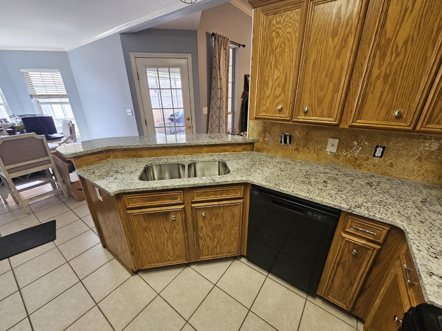A kitchen with wooden cabinets , granite counter tops , a sink and a dishwasher.