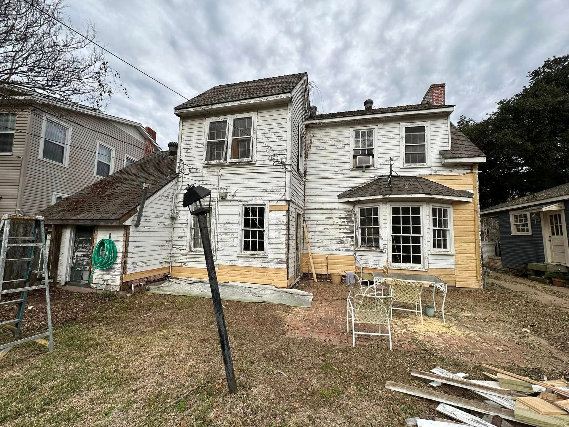 A large white house is being remodeled in a backyard.