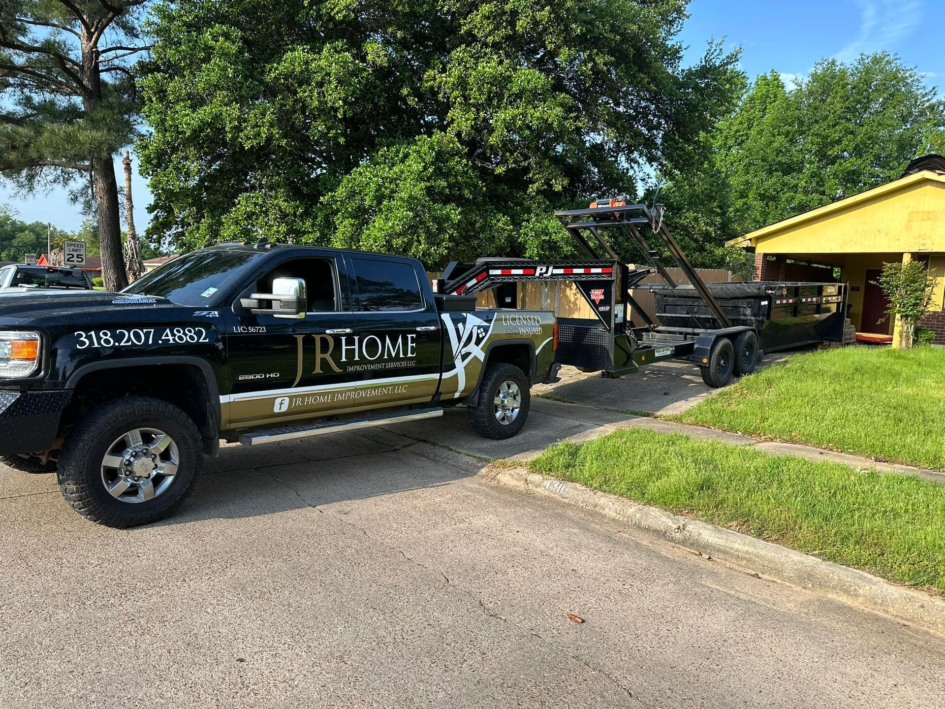A truck with a trailer attached to it is parked in front of a house.