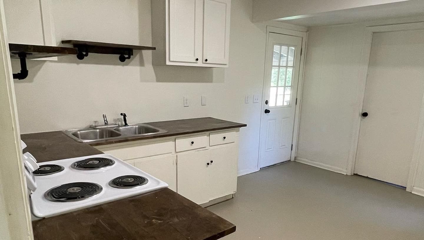 An empty kitchen with a stove , sink , and cabinets.