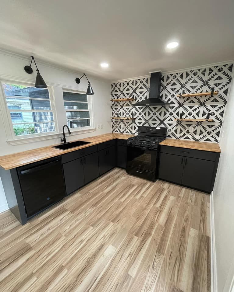 A kitchen with black cabinets , a stove , a sink , and a dishwasher.