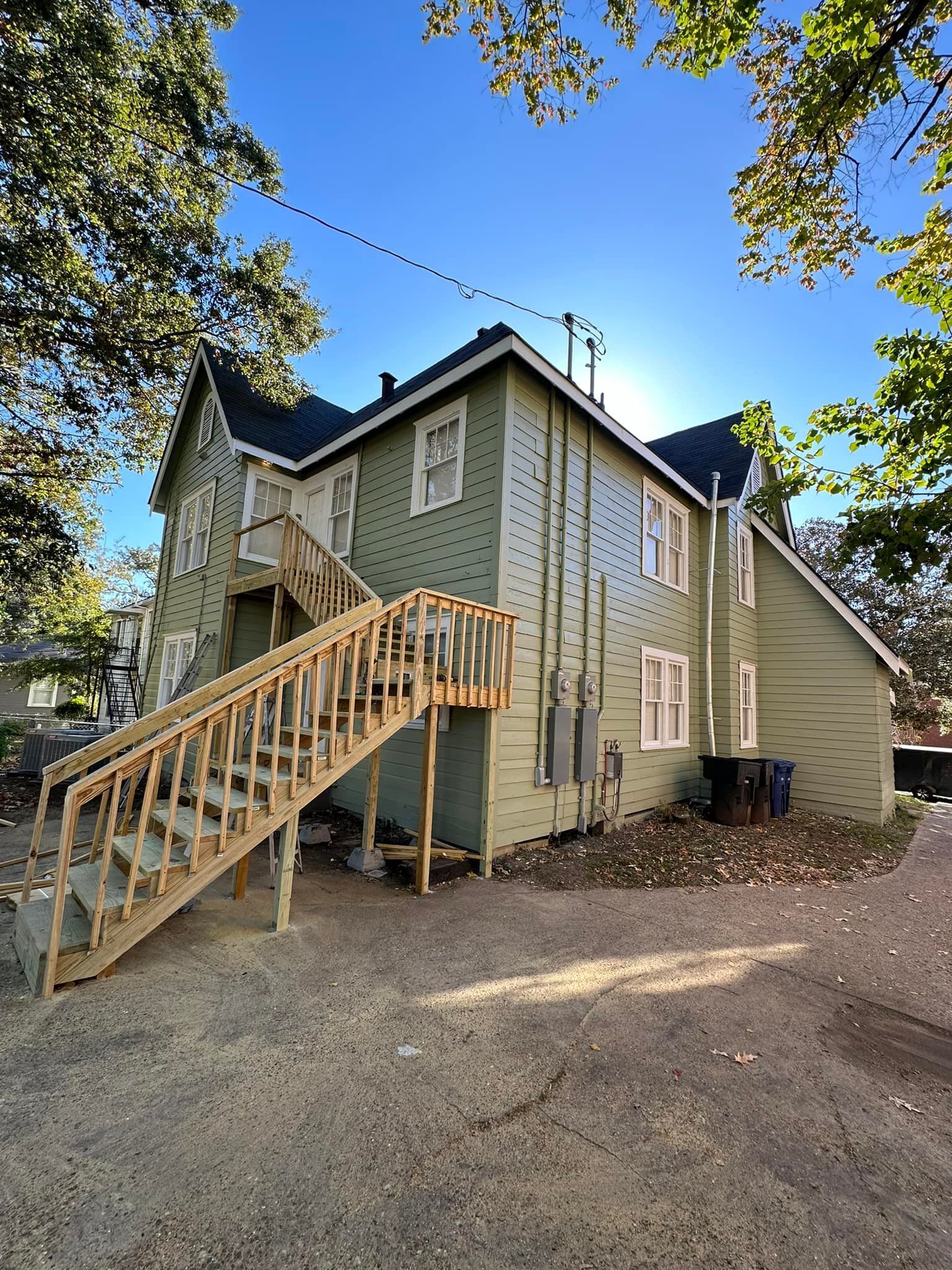 A large green house with stairs leading up to the second floor.