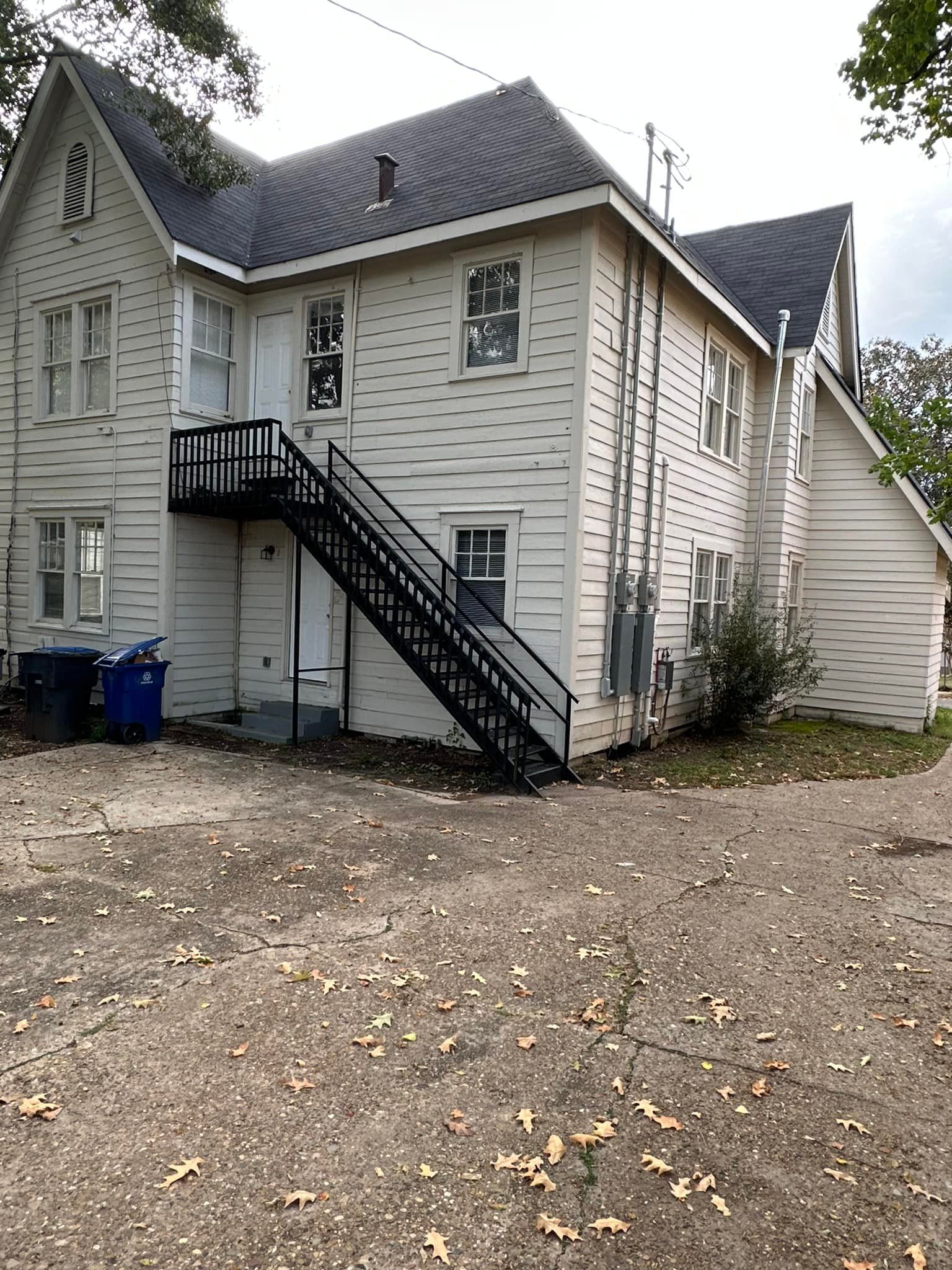 A large white house with stairs leading up to the second floor.