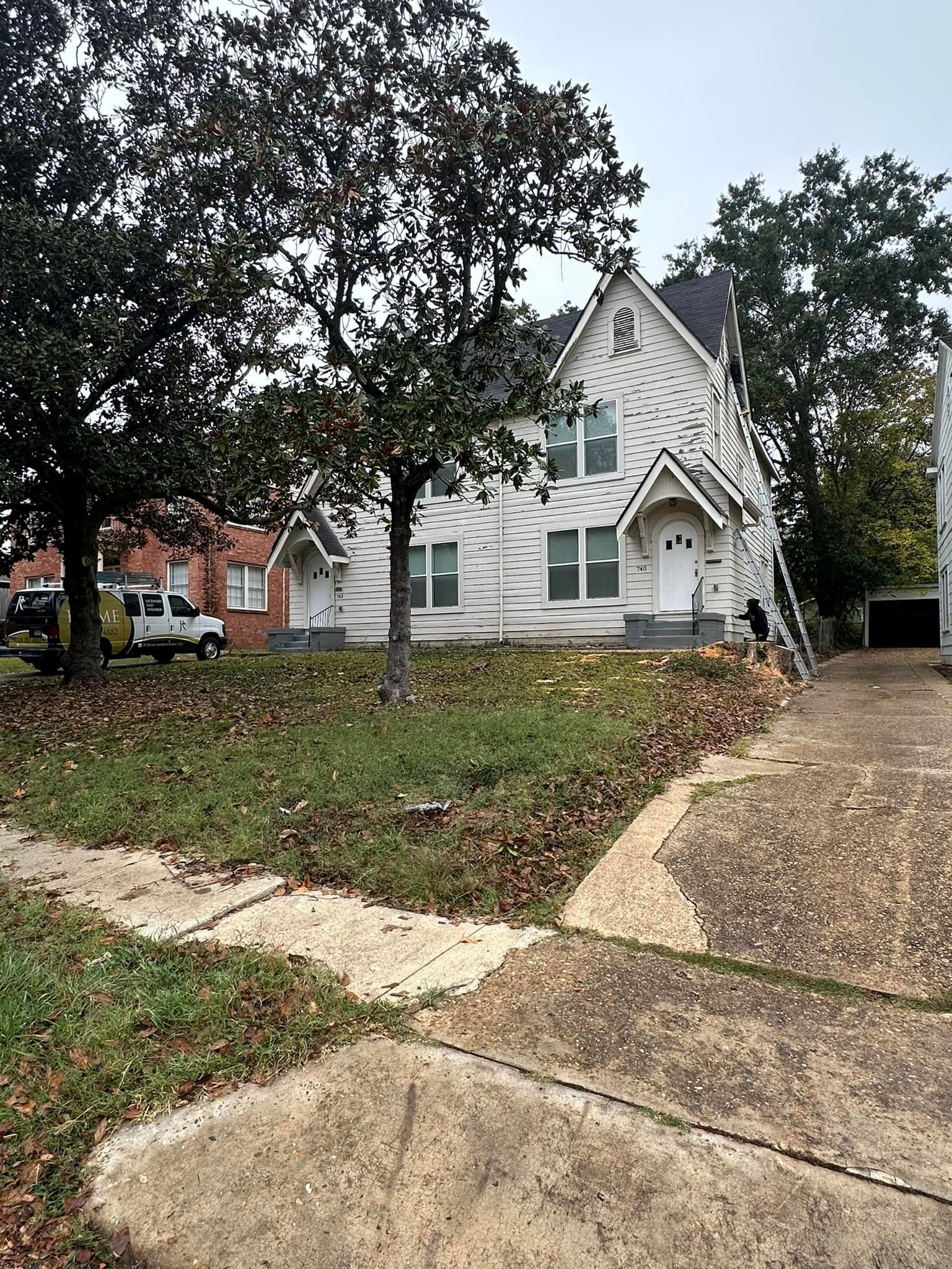 A large white house is sitting on top of a lush green hill.