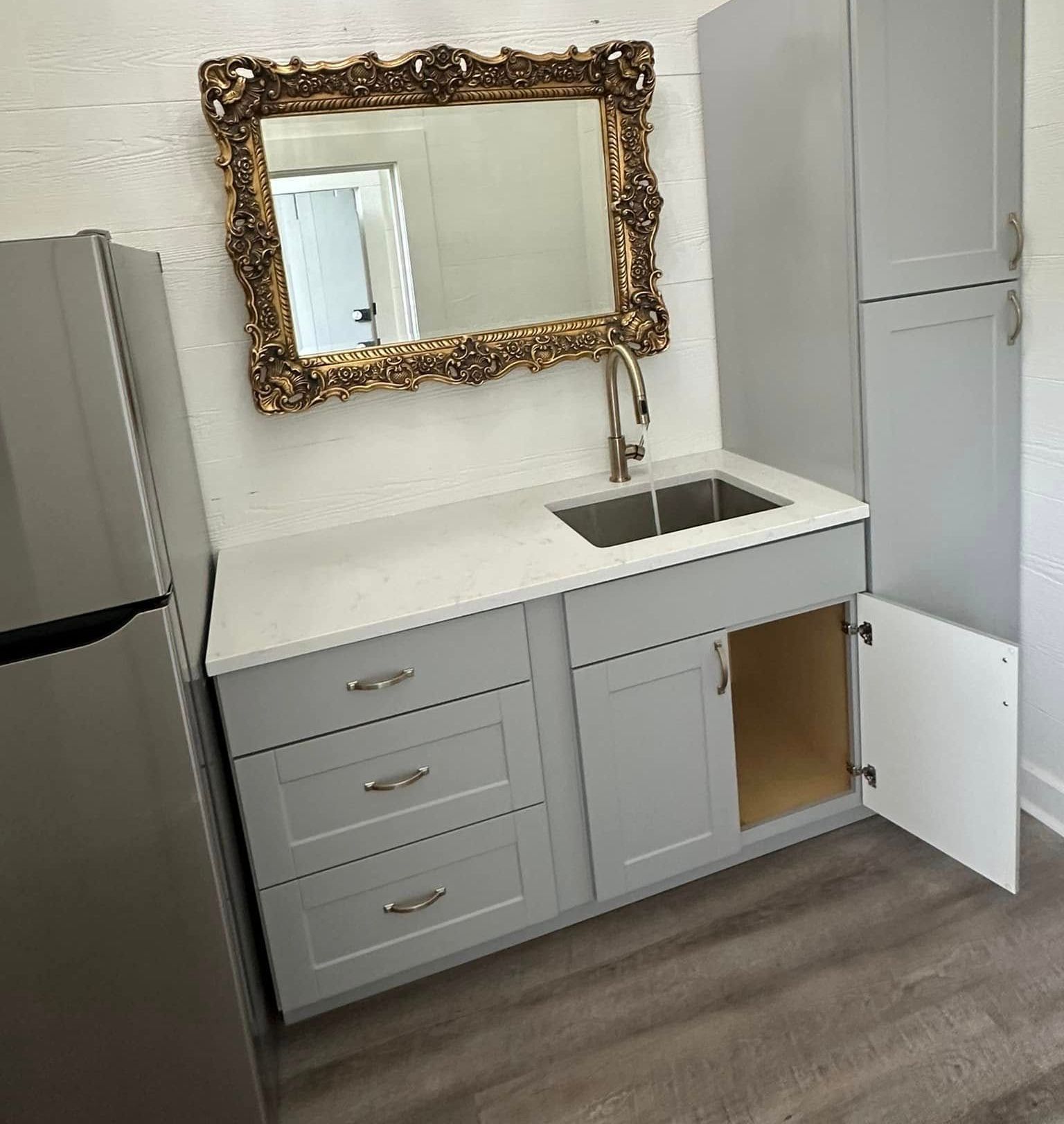 A kitchen counter with a sink and a mirror above it