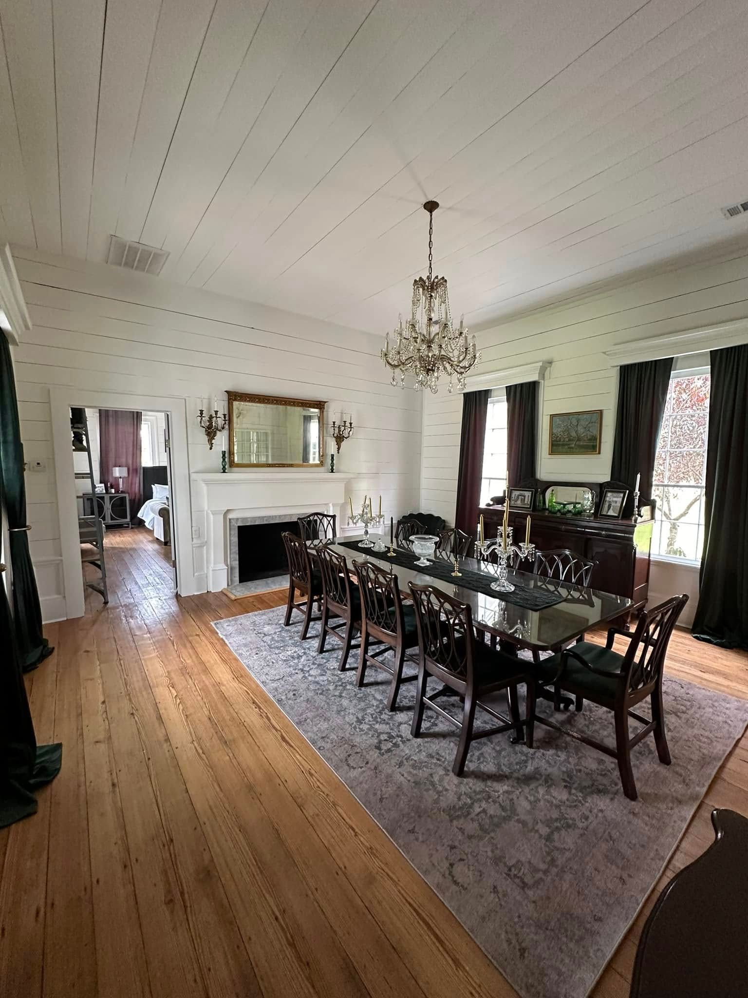 A large dining room with a long table and chairs and a fireplace.