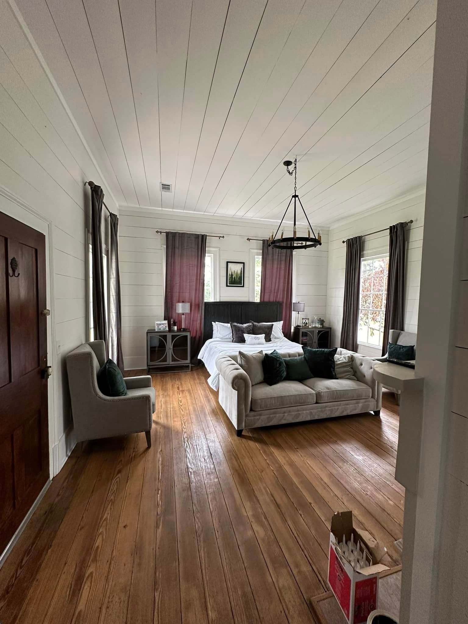 A large room with a bed , couch , chairs and a chandelier.
