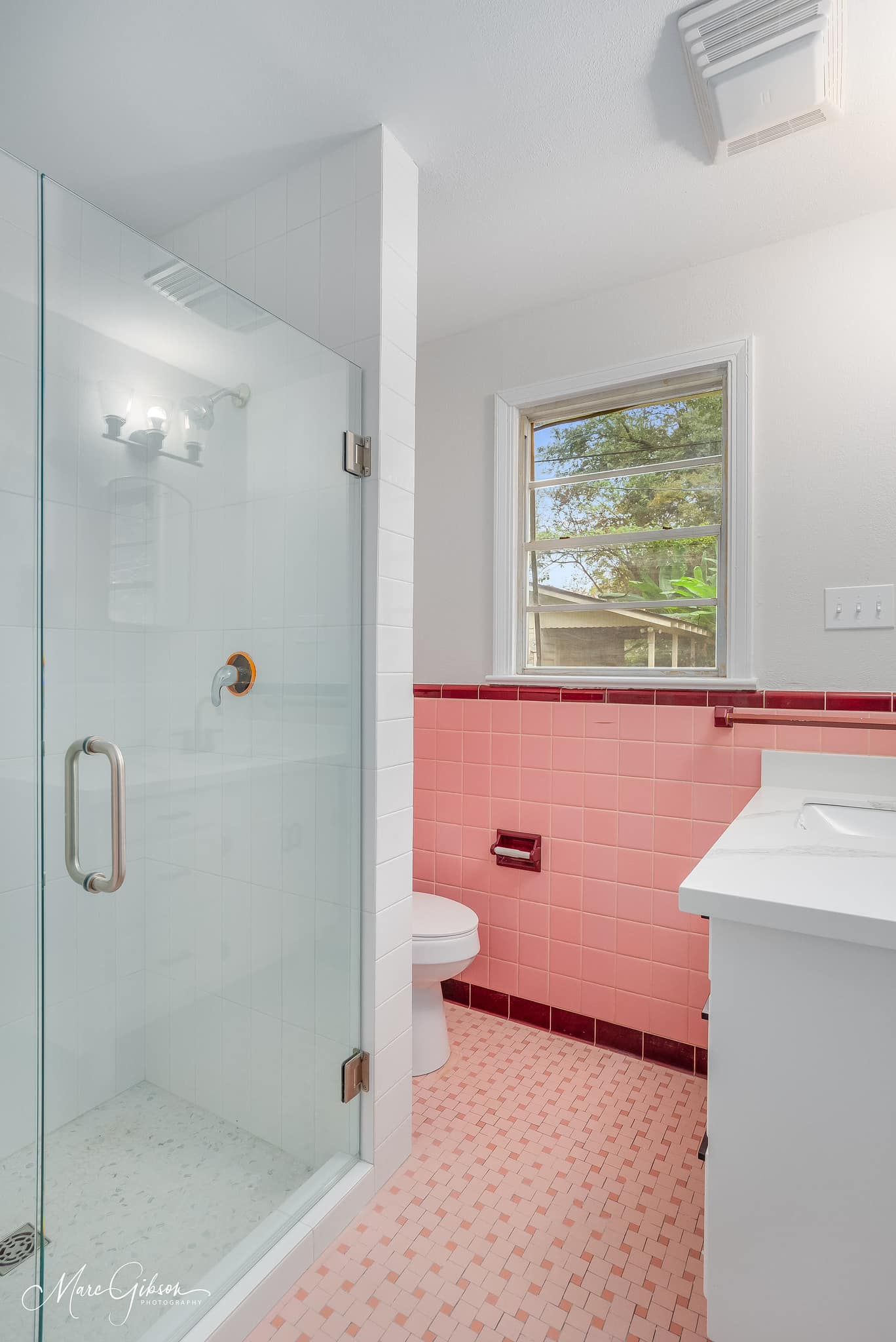 A bathroom with pink tiles and a walk in shower.