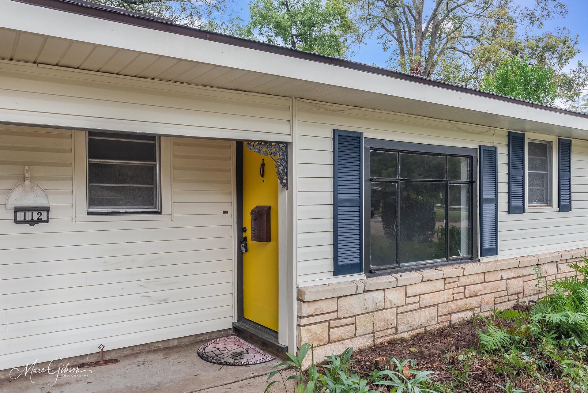 A white house with a yellow door and blue shutters