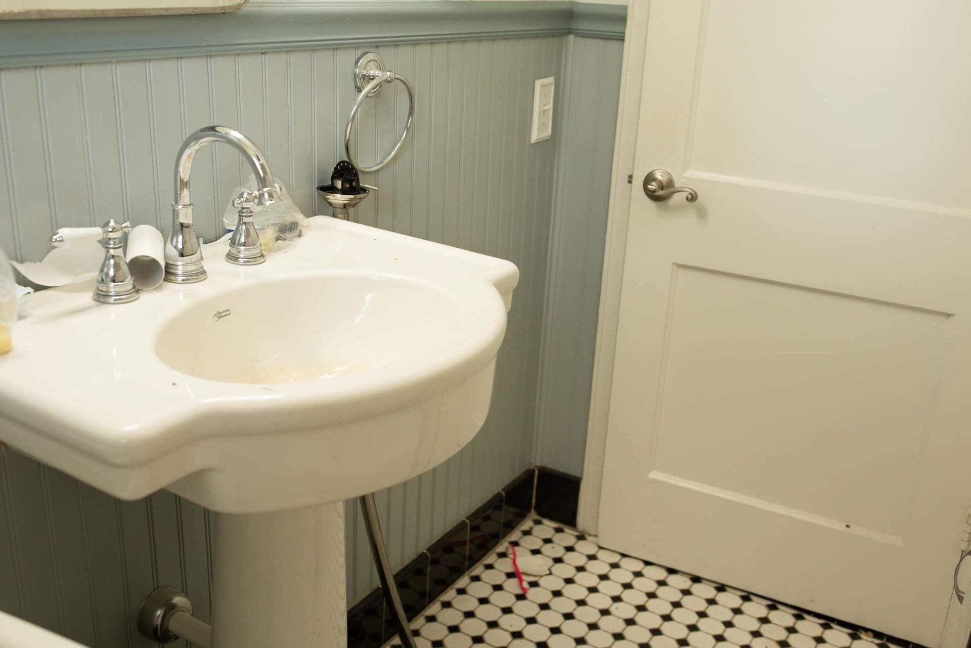A bathroom with a pedestal sink and a black and white tile floor