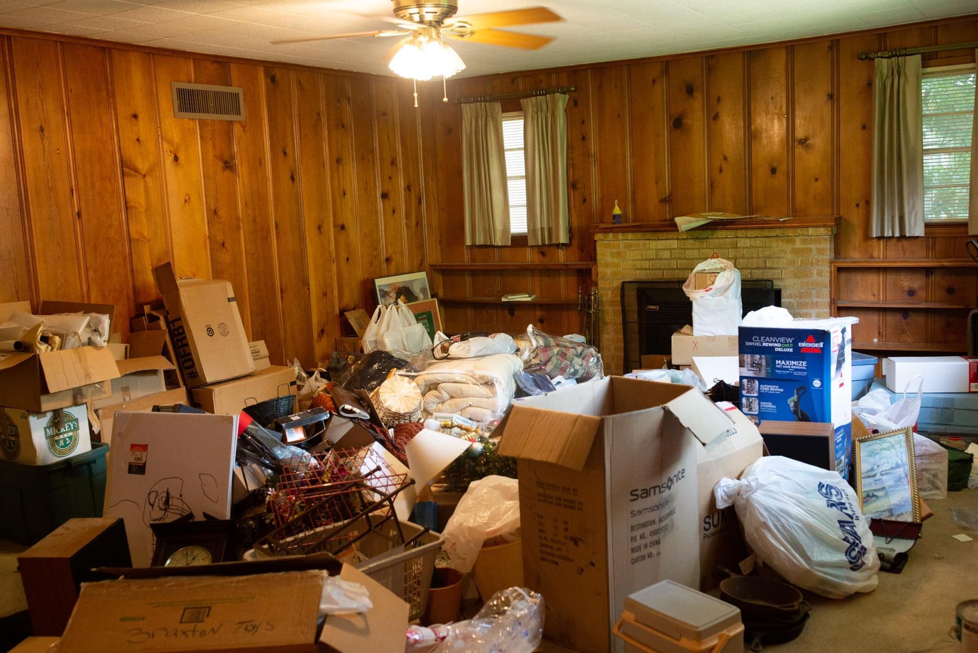 A living room filled with boxes and a ceiling fan
