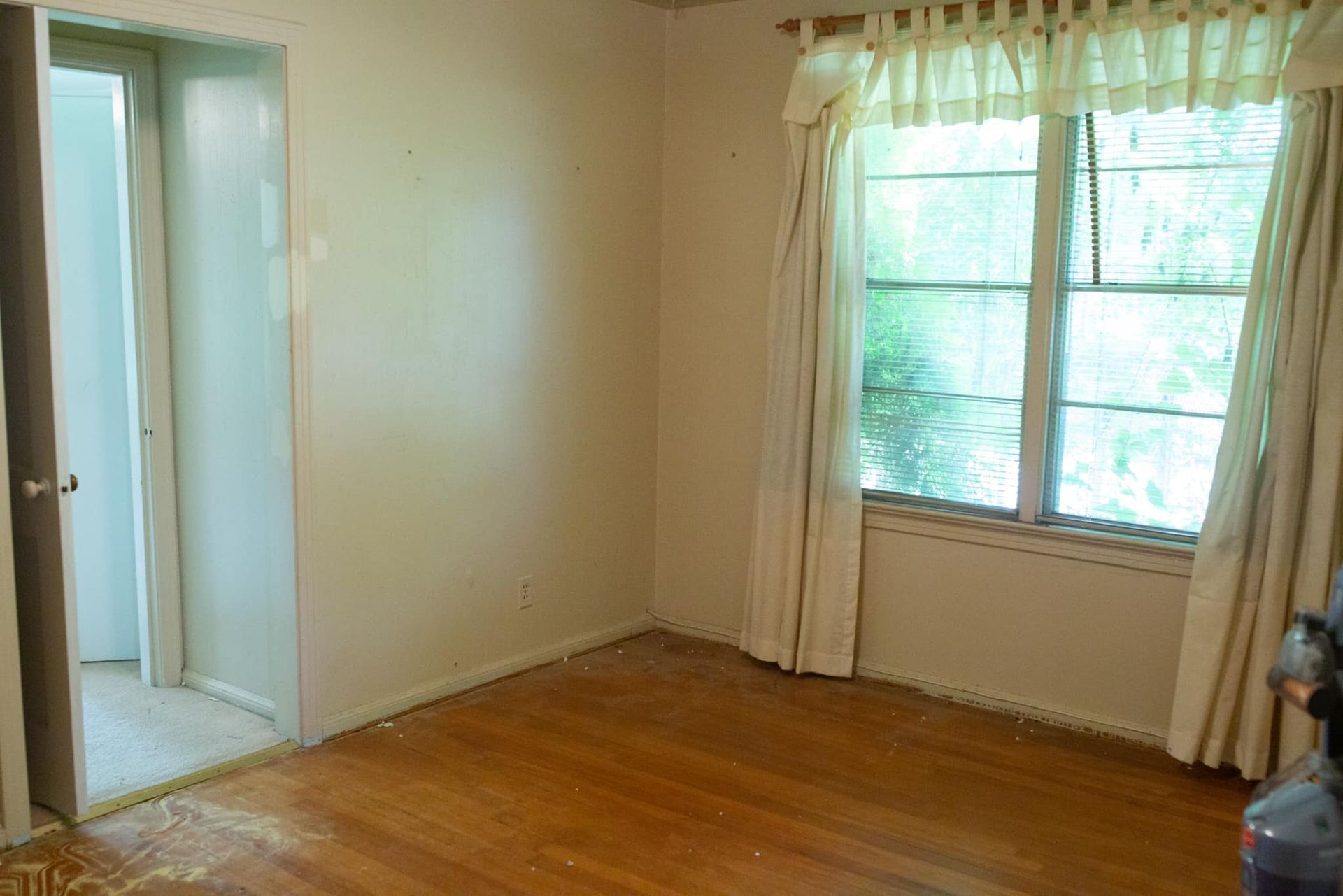 An empty living room with hardwood floors and a window.