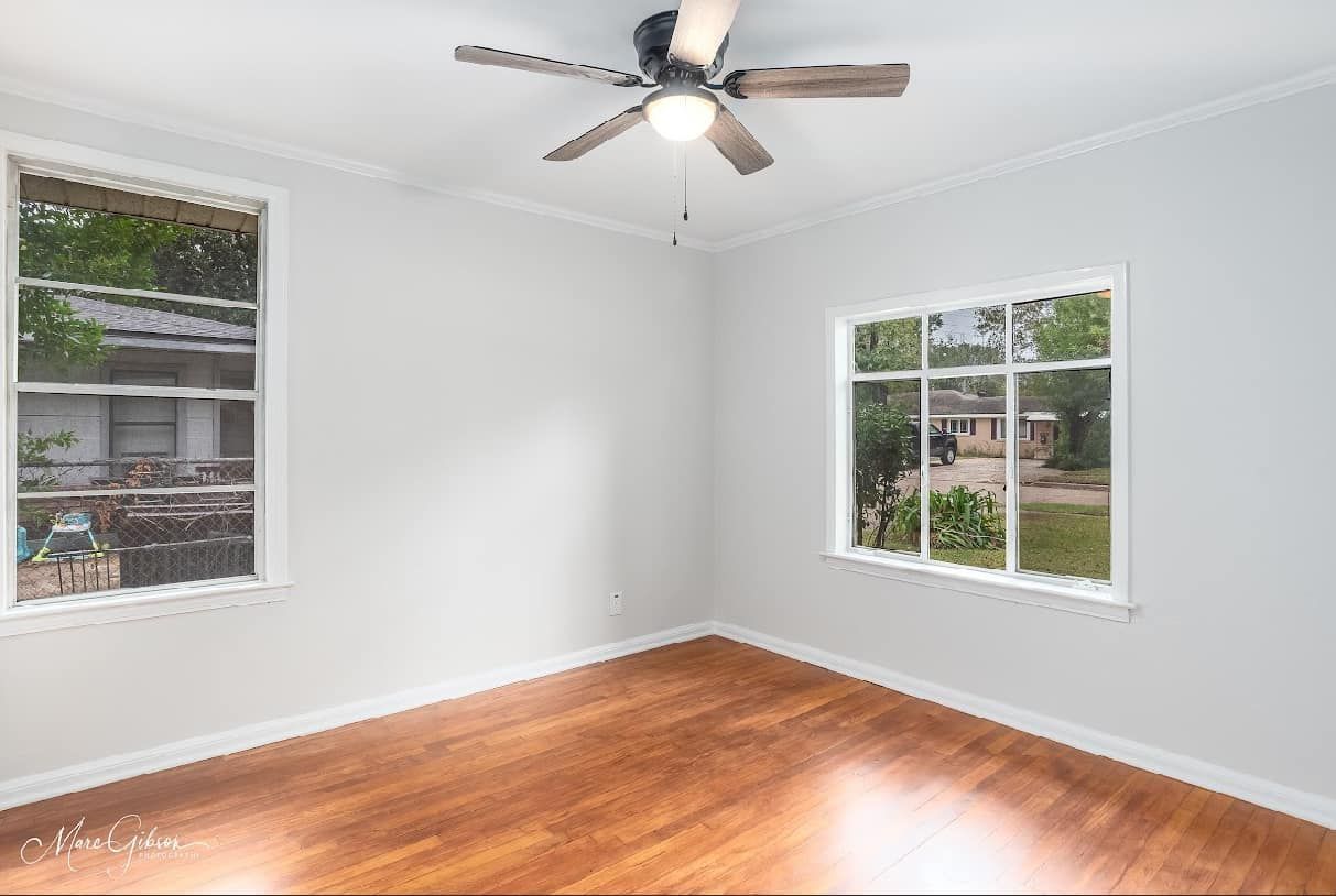 An empty room with hardwood floors and a ceiling fan.