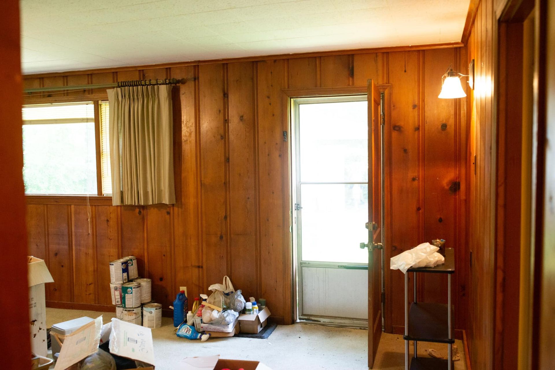 A living room with wood paneling and a lot of boxes on the floor
