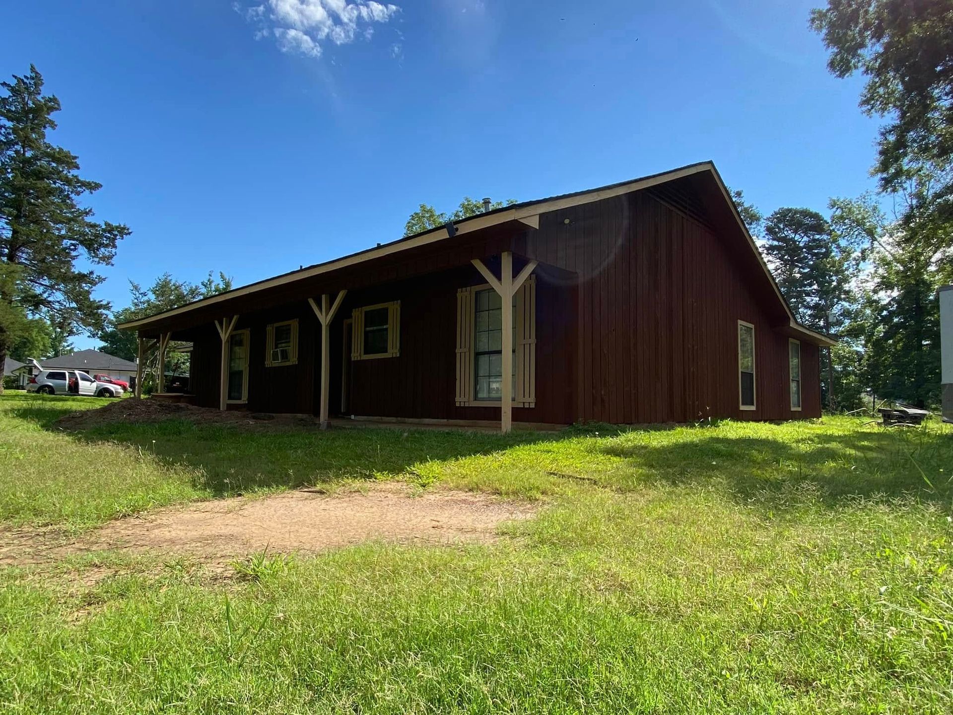 A large red barn is sitting in the middle of a grassy field.