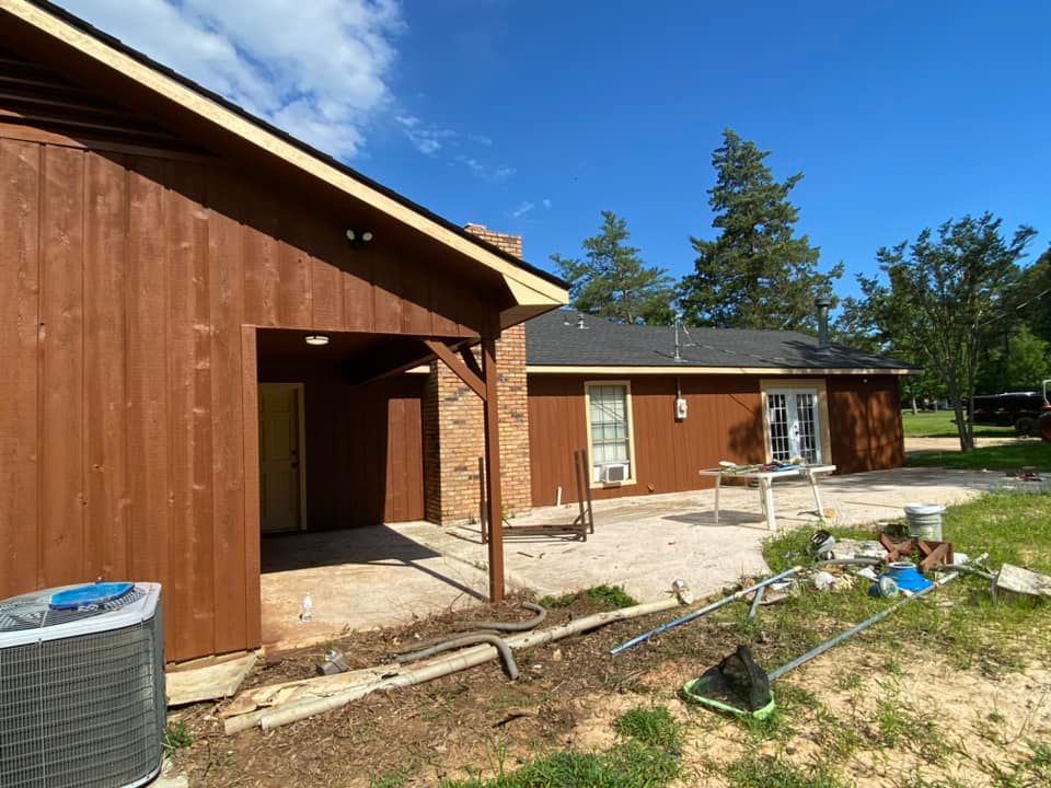A house with brown siding and a patio in front of it.