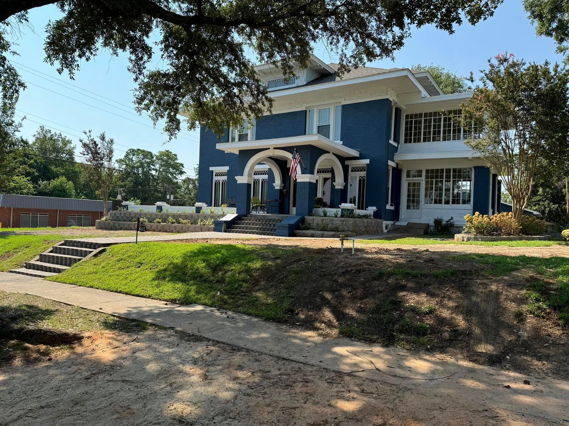 A large blue and white house is sitting on top of a grassy hill.