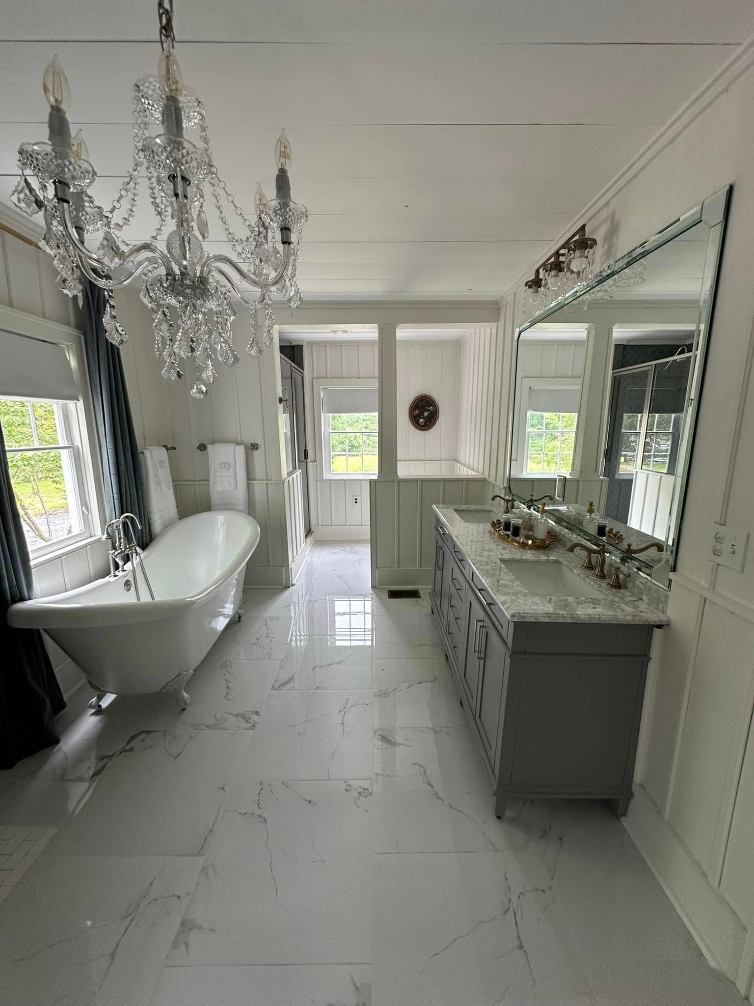 A bathroom with a bathtub , sinks , mirrors and a chandelier.