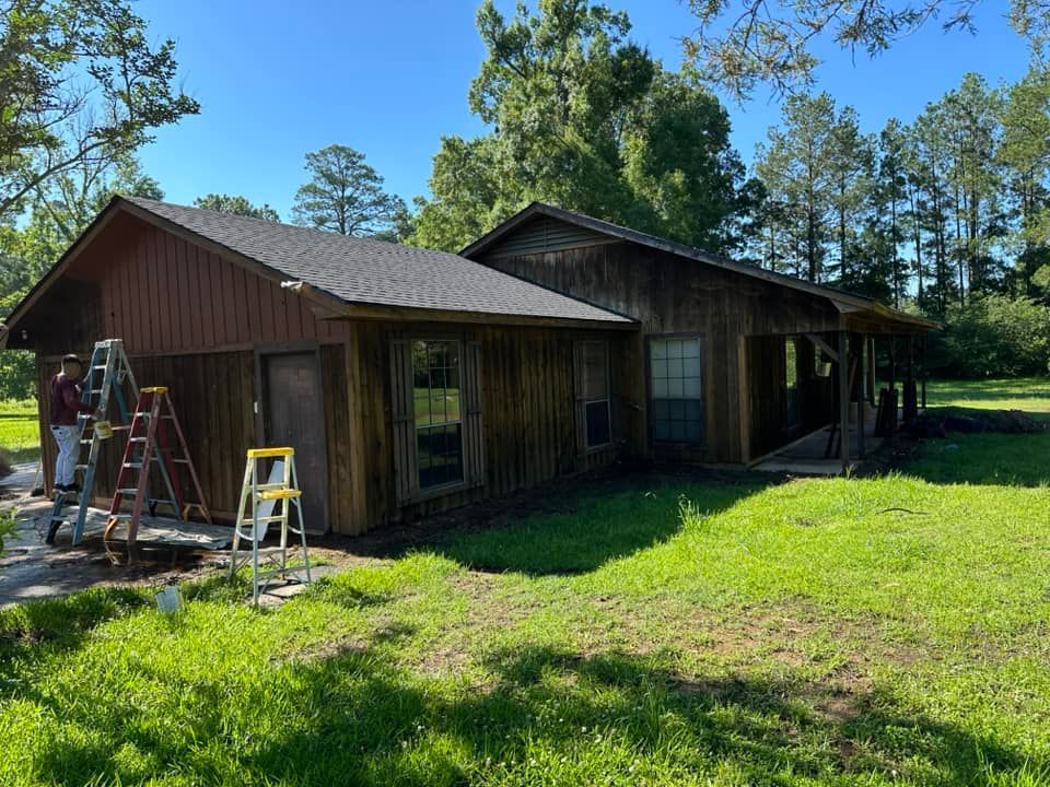 A house is being painted in a field with a ladder in front of it.