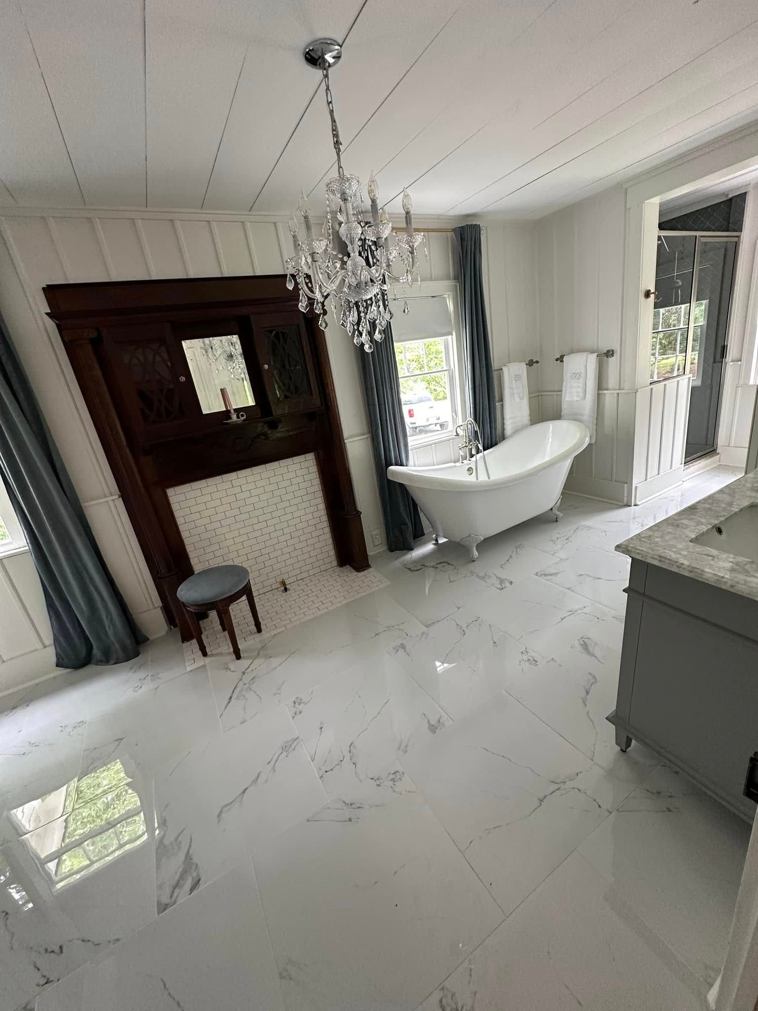A bathroom with a claw foot tub , sink , mirror and fireplace.