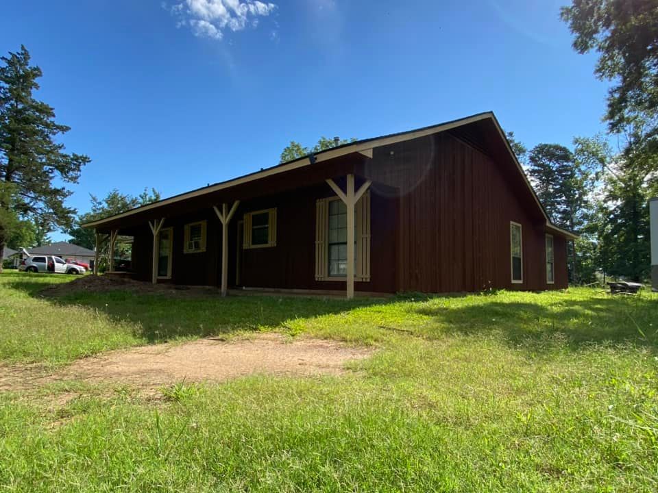A large red barn is sitting in the middle of a lush green field.