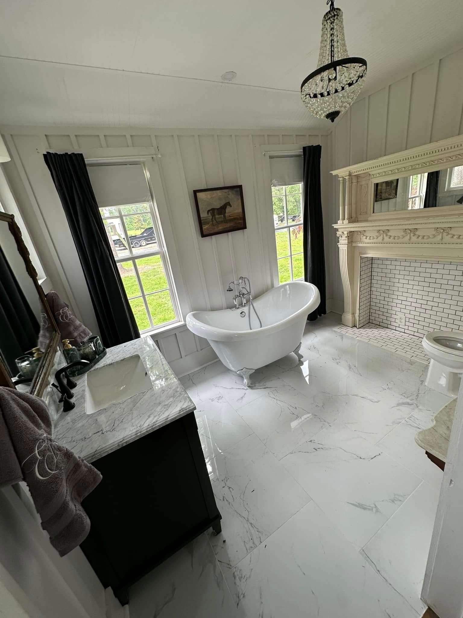 A bathroom with a tub , sink , mirror and fireplace.