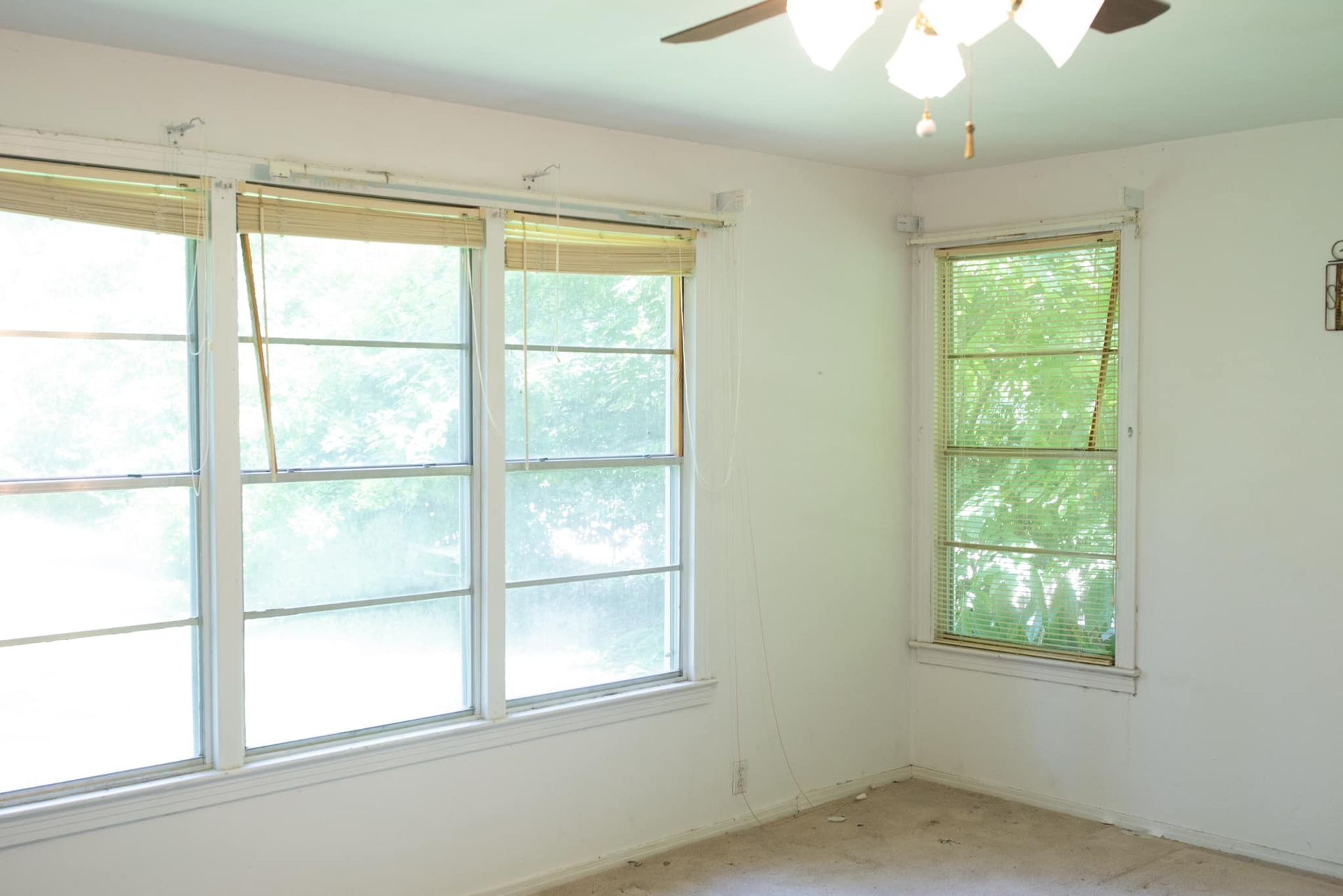 An empty room with two windows and a ceiling fan
