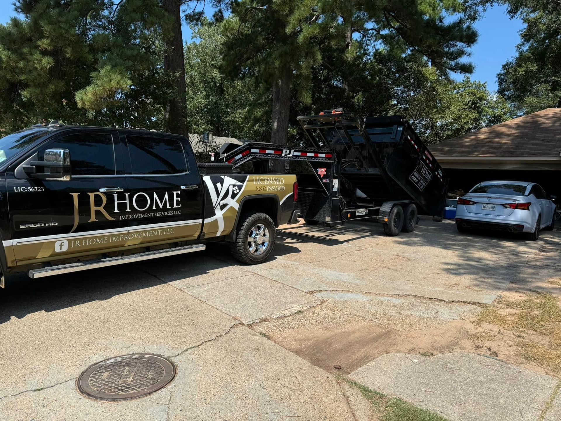 A dump truck is parked in a driveway next to a car.