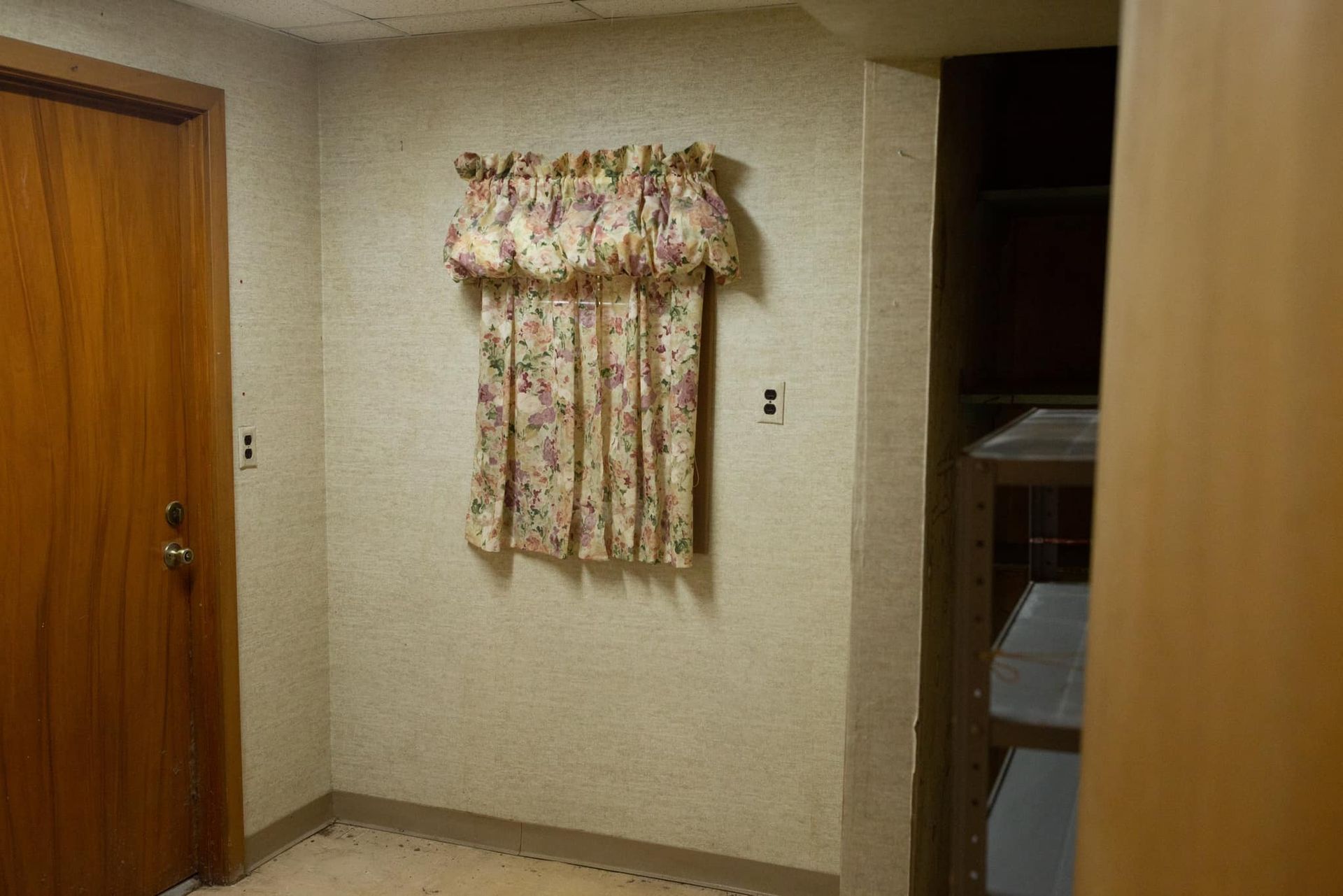 A room with a door and curtains on the wall.