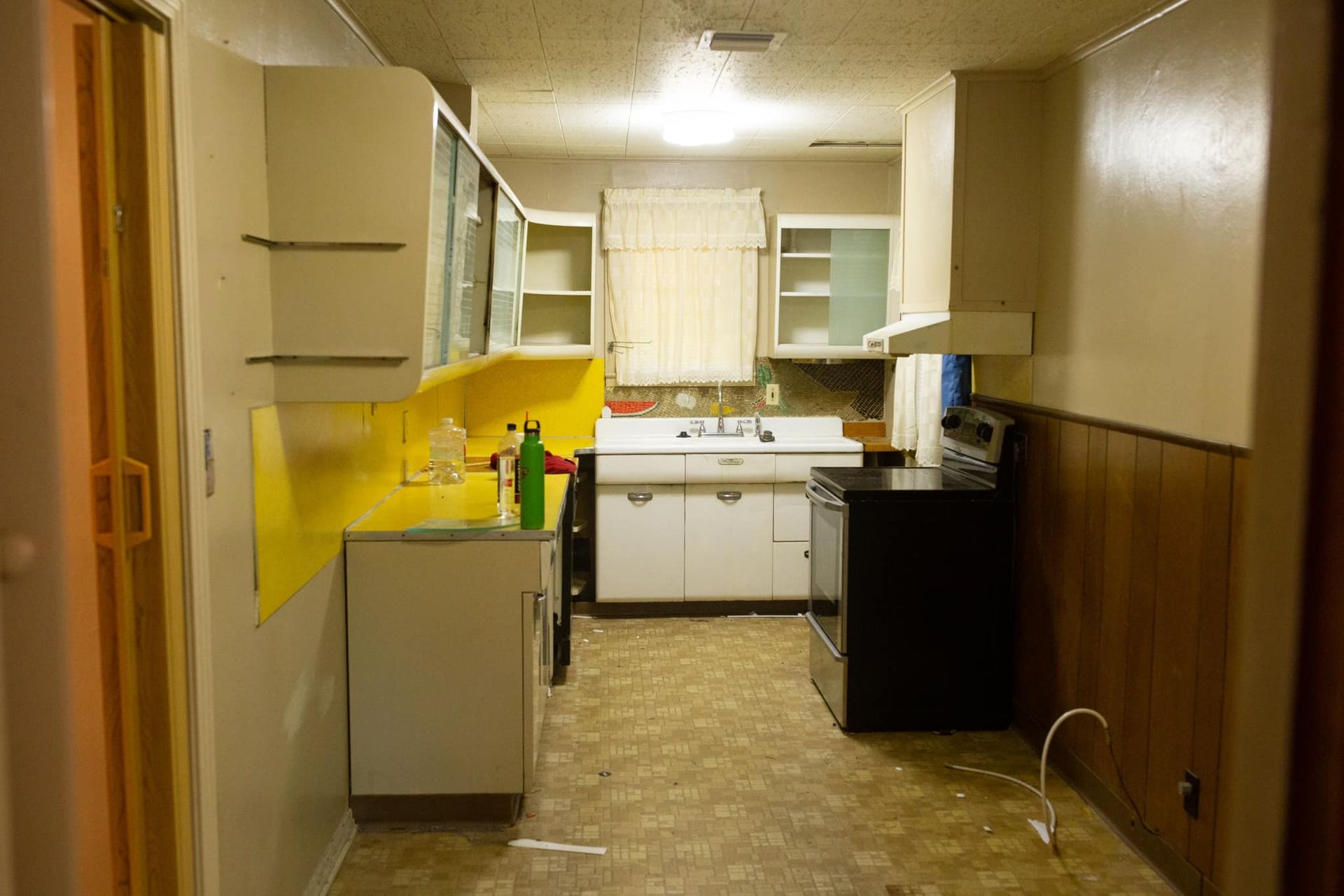 An empty kitchen with white cabinets and a black stove