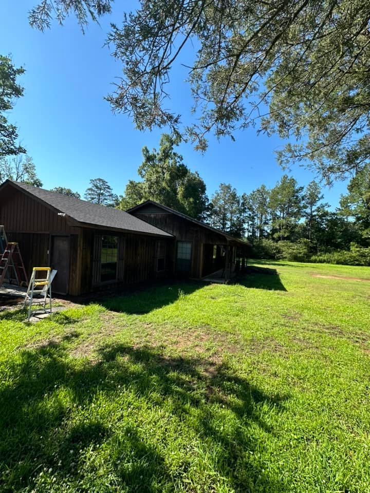 A large house is sitting in the middle of a lush green field.
