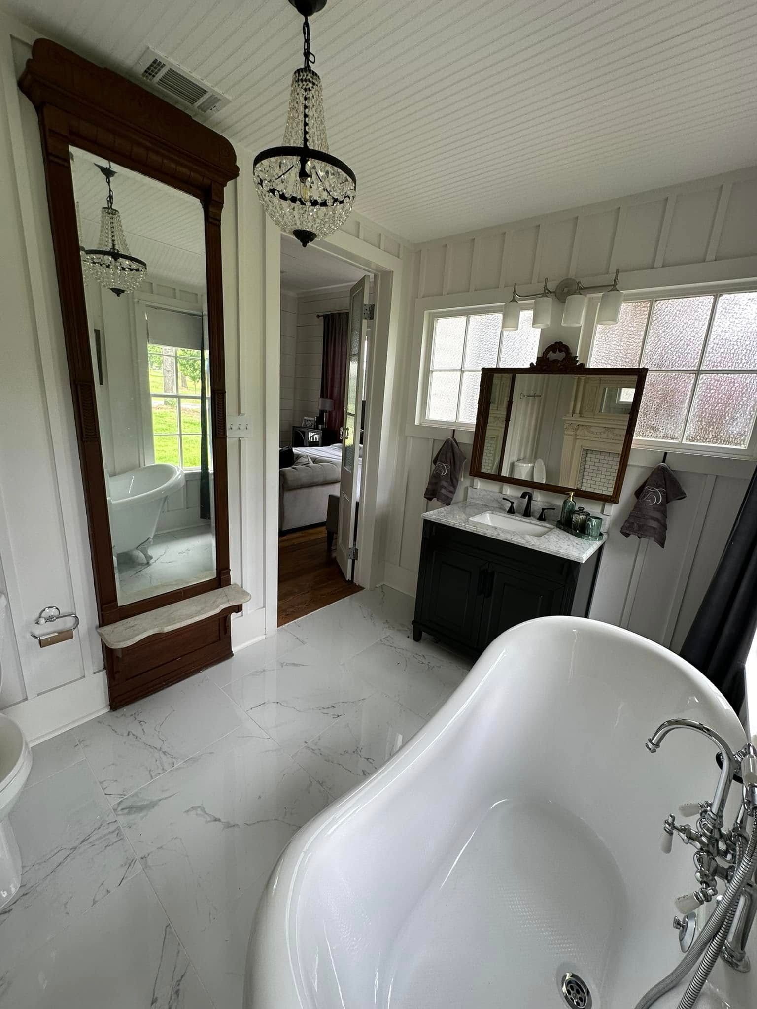 A bathroom with a tub , sink and mirror.