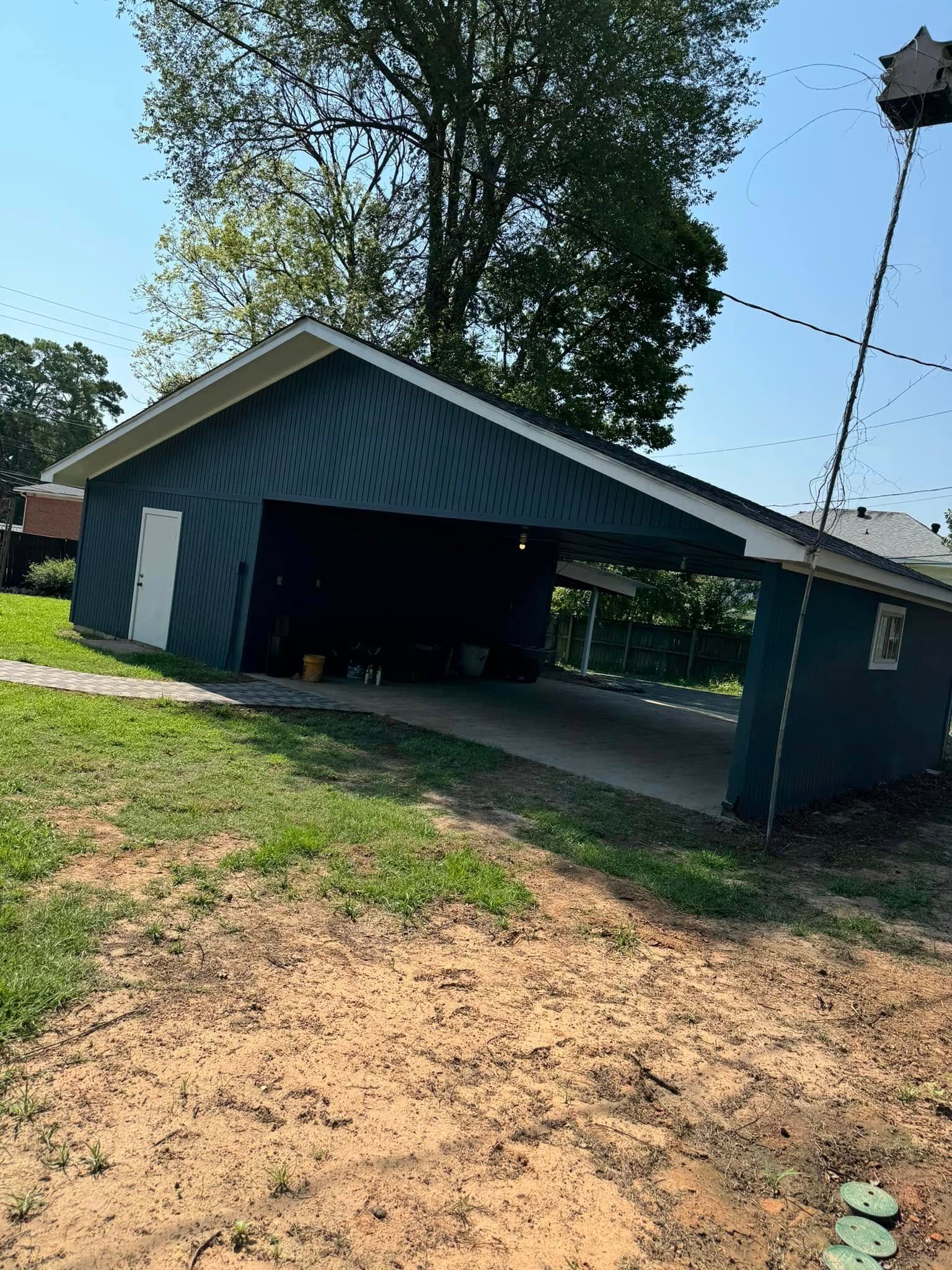 A blue garage with a white door and a tree in the background.