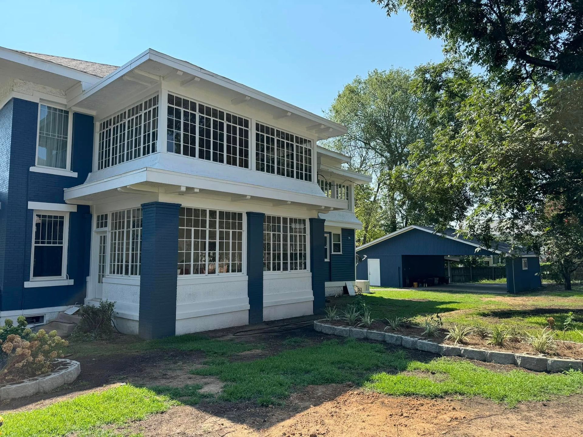 A large blue and white house with a large porch and a garage.