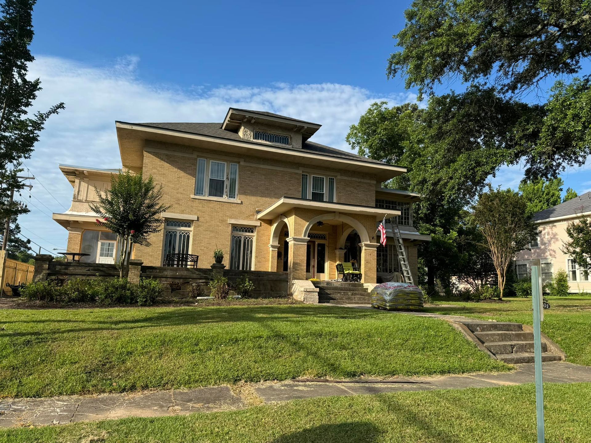 A large house with a lot of windows is sitting on top of a lush green lawn.