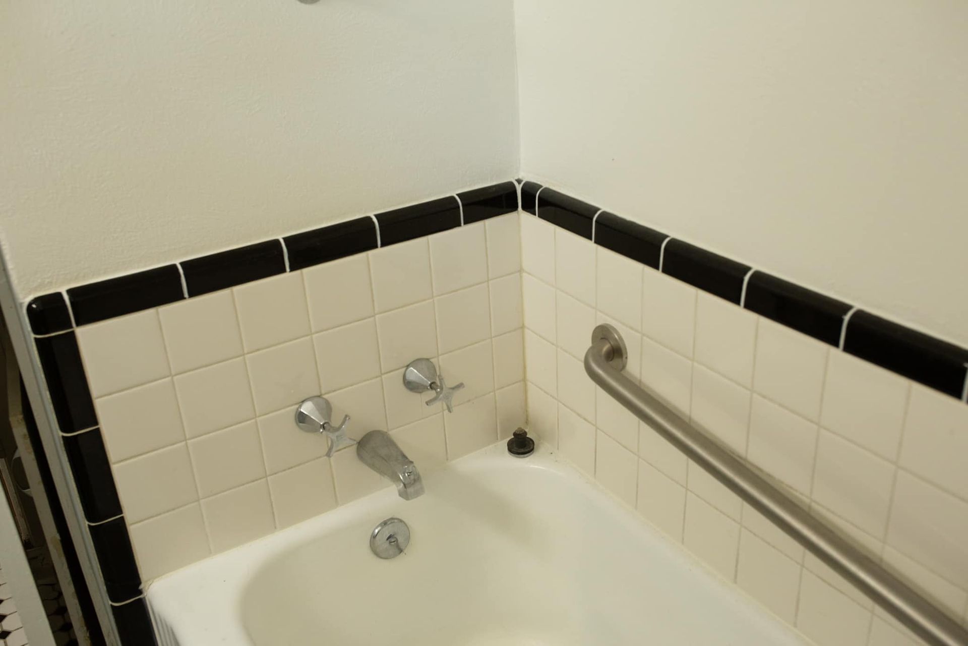 A bathtub in a bathroom with black and white tiles