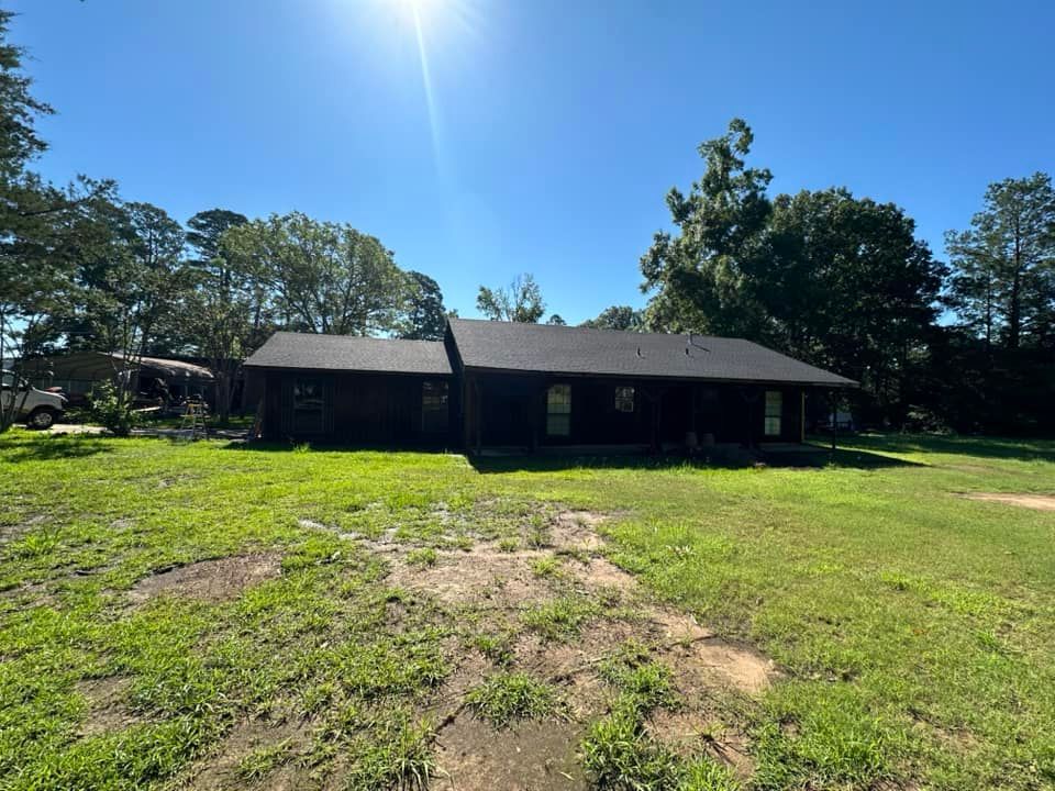 A large house is sitting in the middle of a lush green field.
