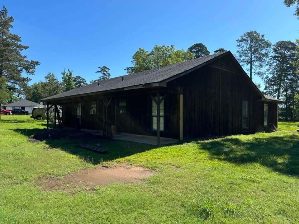A large wooden house is sitting in the middle of a lush green field.
