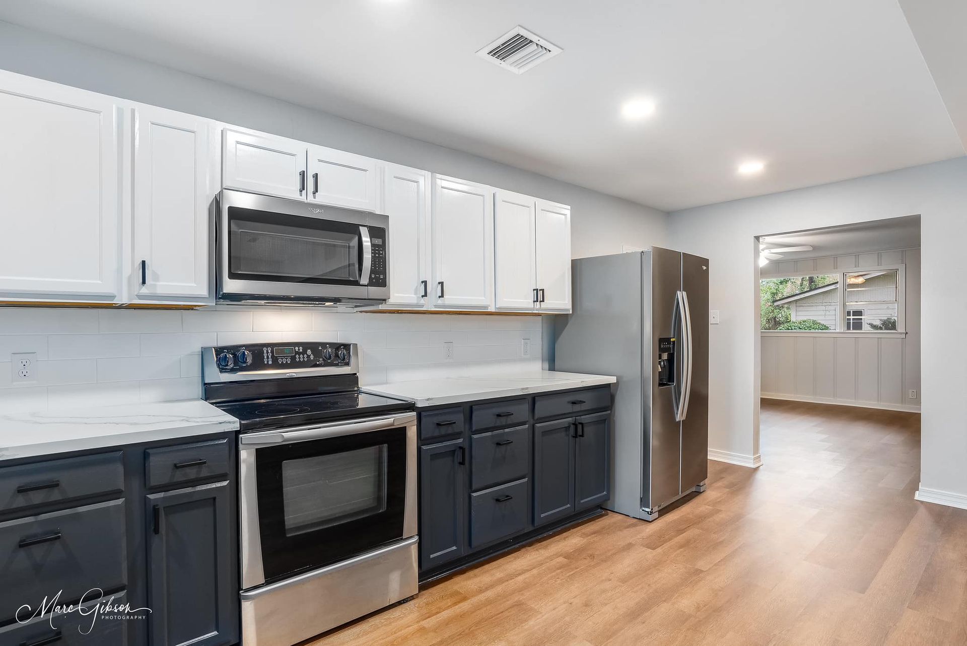 A kitchen with black cabinets , stainless steel appliances , a stove , microwave and refrigerator.