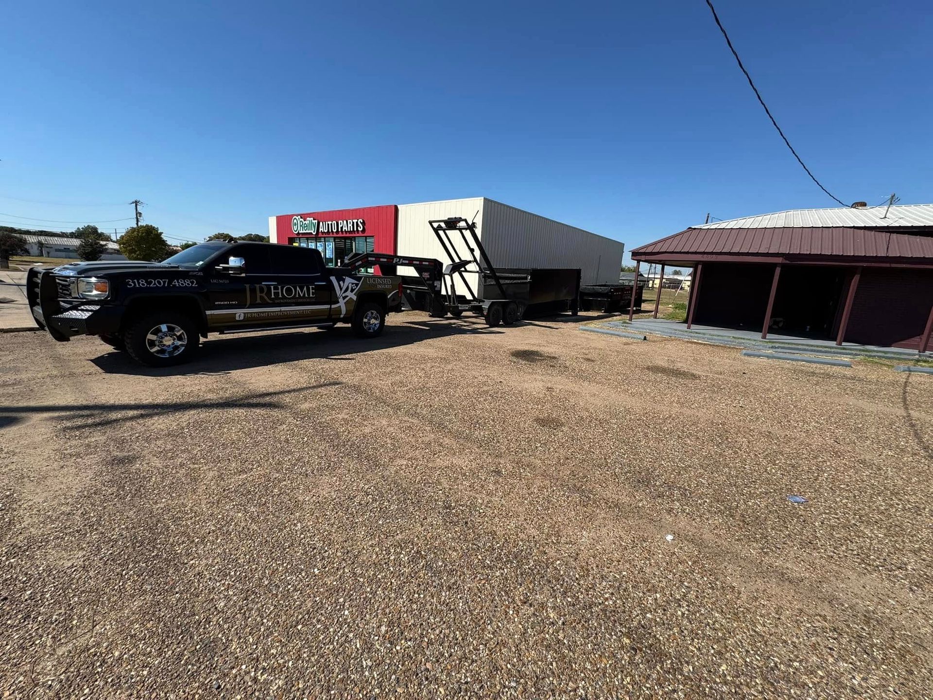 A truck is towing a trailer in a gravel lot.