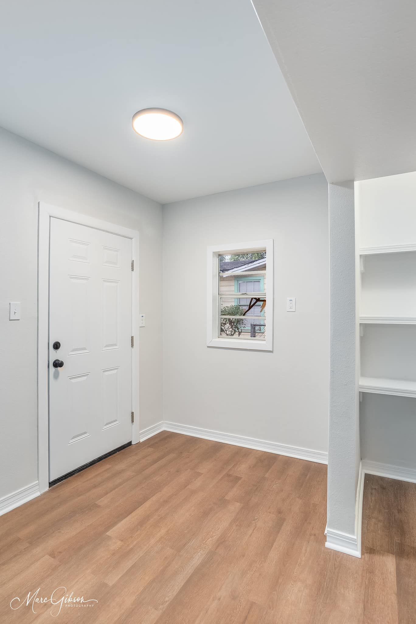 An empty room with hardwood floors and a white door.