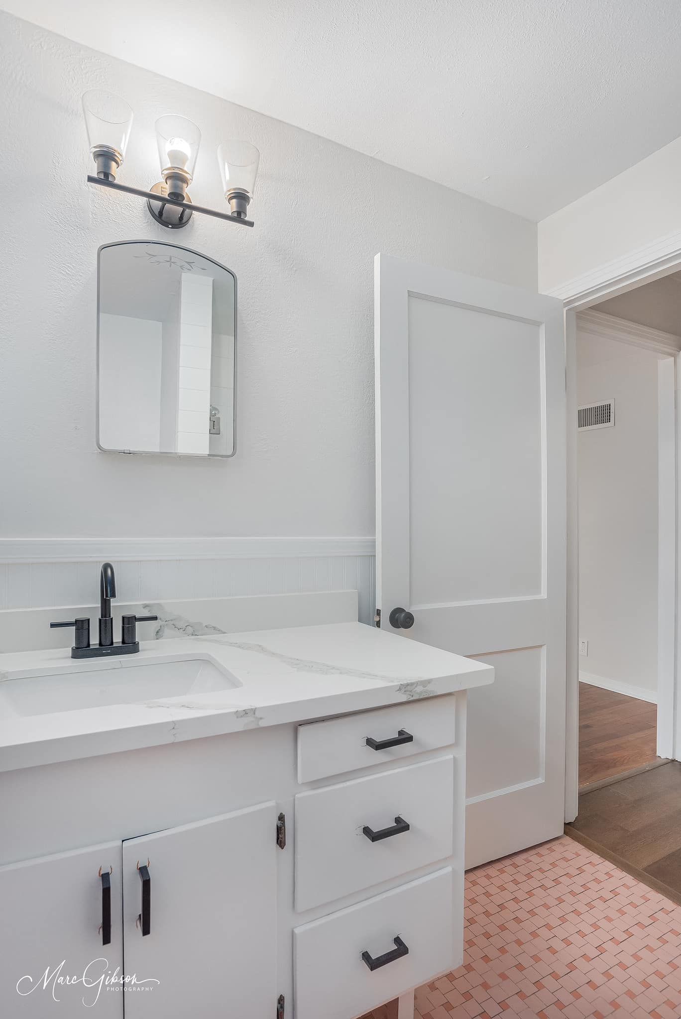 A bathroom with a sink , mirror and drawers.
