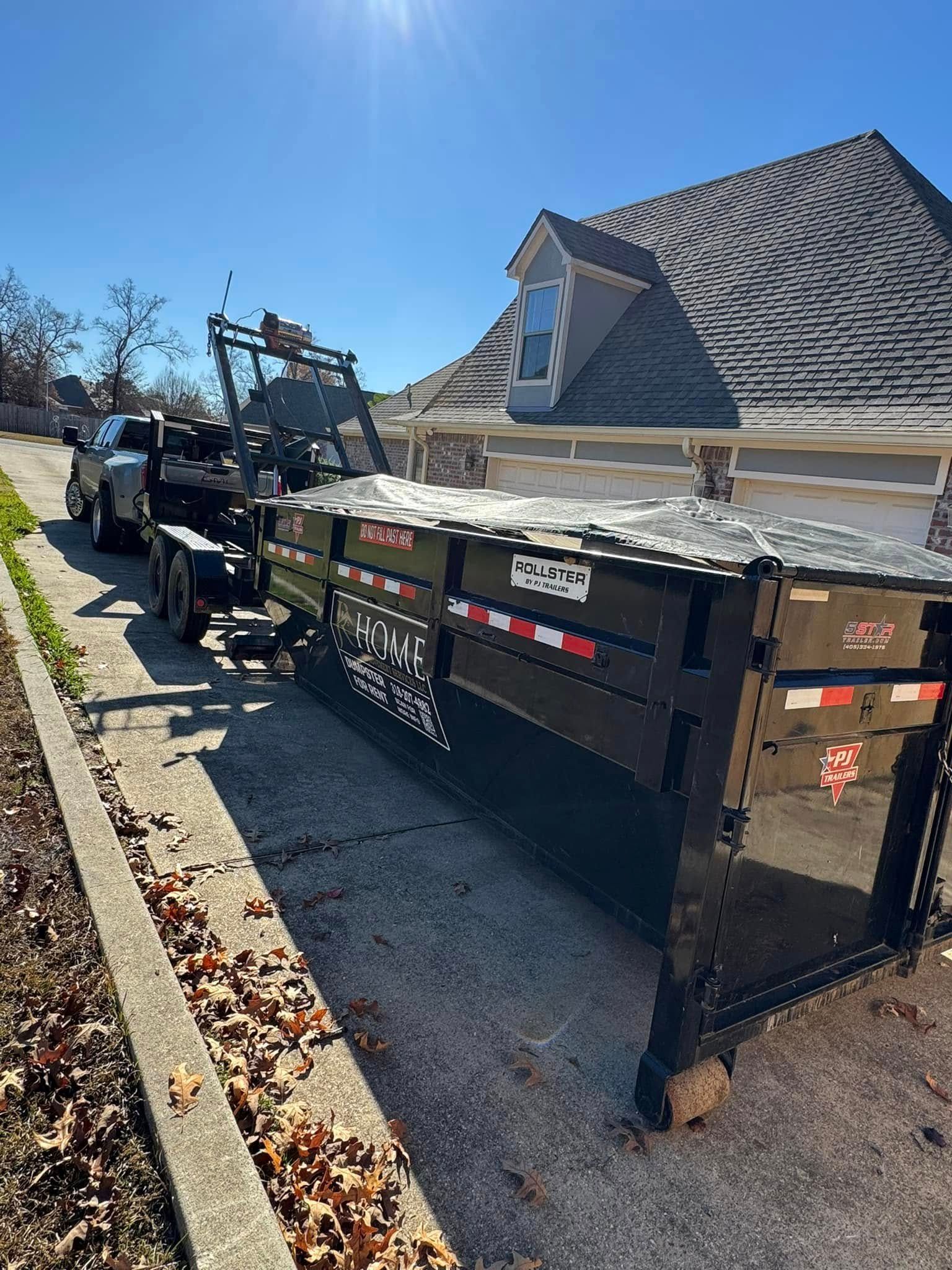 A dumpster is sitting on the side of the road next to a house.