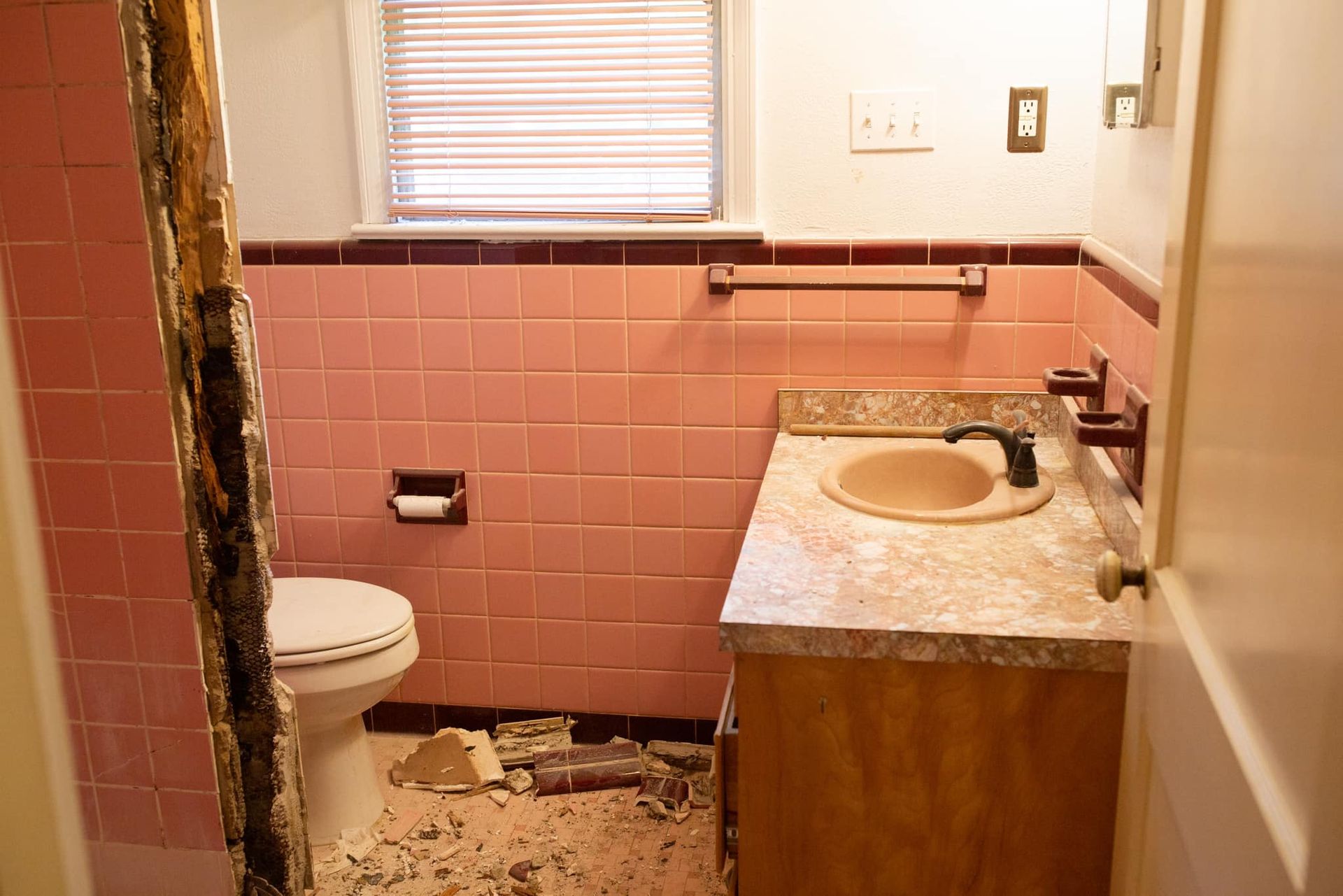 A bathroom with pink tiles and a sink and toilet