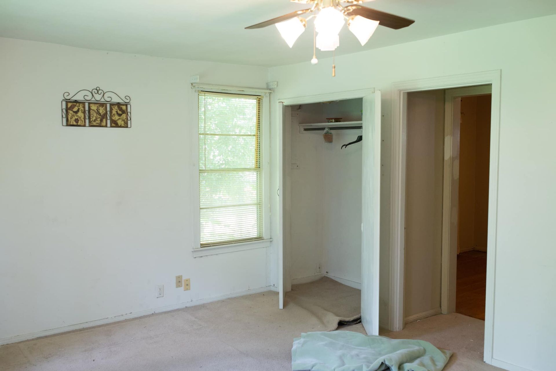 An empty bedroom with a ceiling fan and a window.
