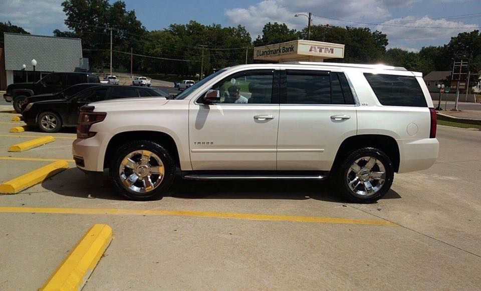 White SUV parked in a yellow-lined lot under a partly cloudy sky