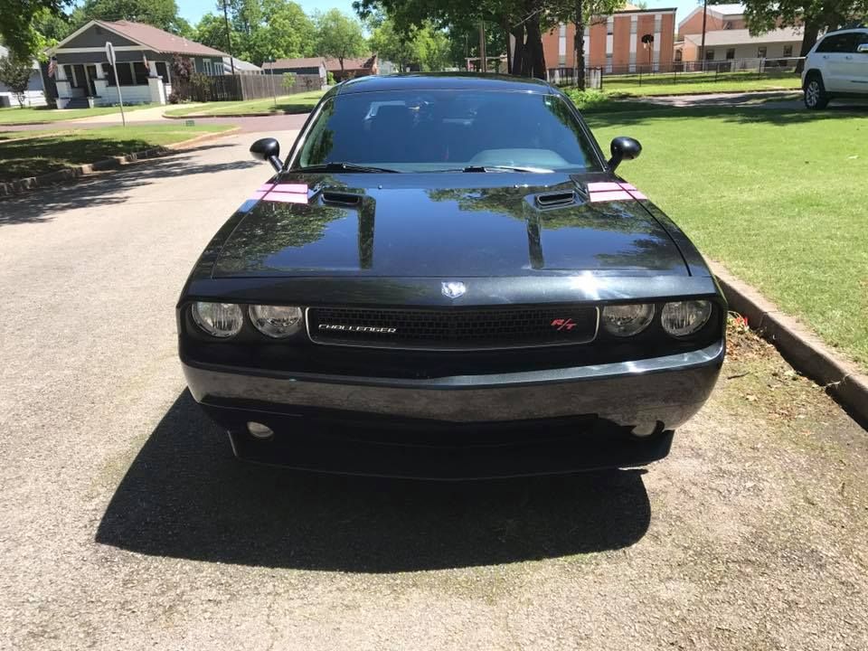 Black Dodge Challenger parked on a driveway in a residential neighborhood, front view