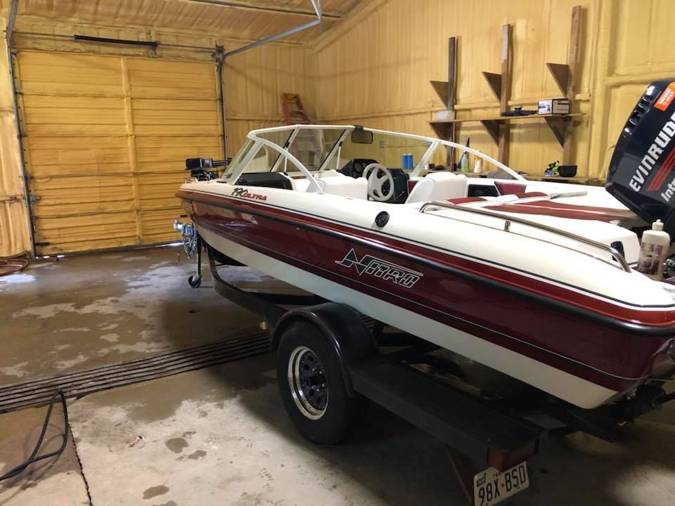 Red and white speedboat on a trailer inside a garage with wet concrete floor.
