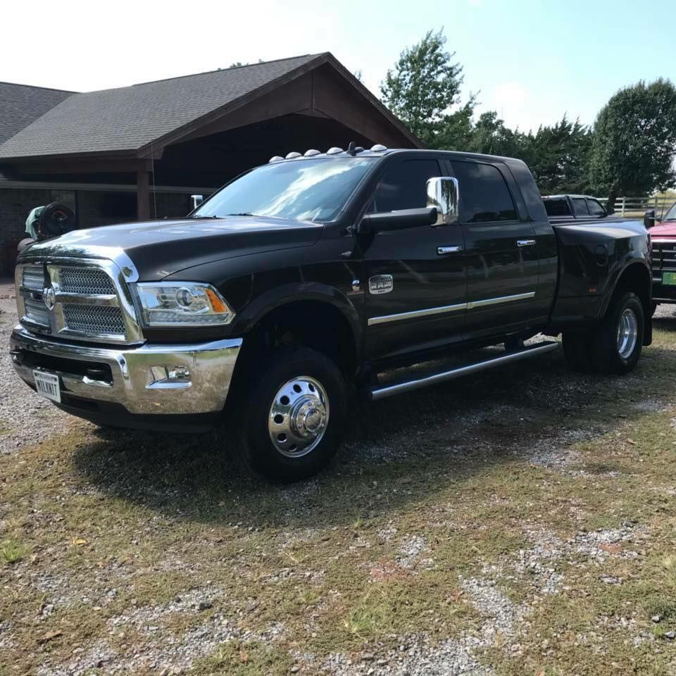Black pickup truck parked in front of a house on a gravel driveway